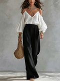 Top blanco de hombros descubiertos  y pantalón negro de pierna ancha